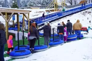 people waiting to ride the conveyor to the top of the snow tubing hill at rowdy bear